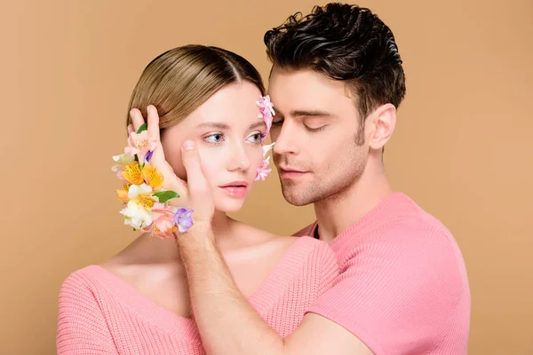 Bonito Homem Tocando Rosto Namorada Com Flores Rosto Isolado Bege — Fotografia de Stock