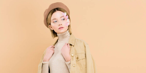 красивая женщина с цветами на лице в берете и стоя изолированы на бежевый
 
