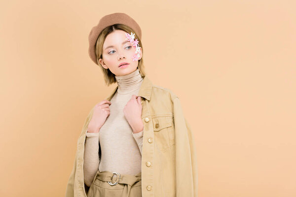 красивая девушка с цветами на лице в берете и стоя изолированы на бежевый
 