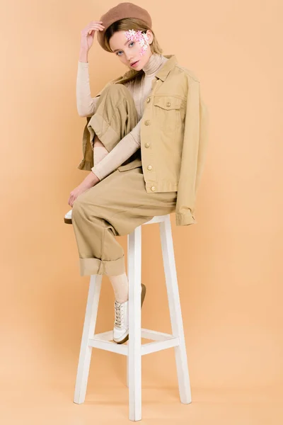 Trendiges Mädchen Baskenmütze Sitzt Auf Stuhl Isoliert Auf Beige — Stockfoto
