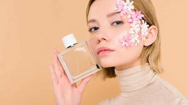 ベージュに分離された香水のボトルを保持している顔に花を自信を持って女性 — ストック写真