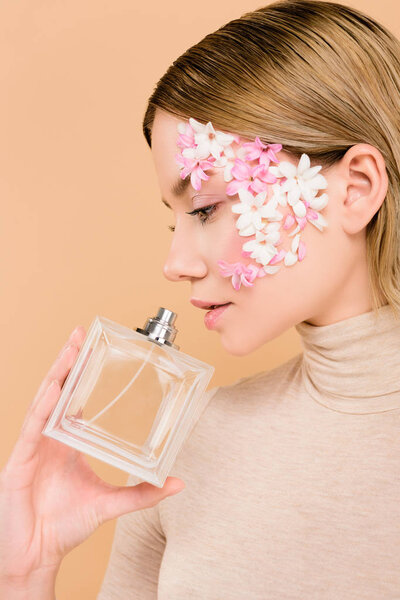 attractive with flowers on face smelling perfume isolated on beige