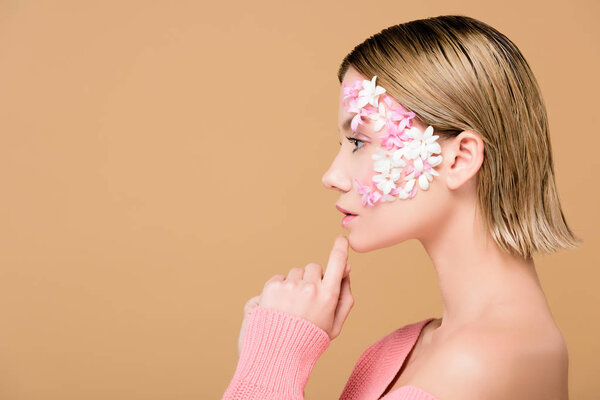 side view of attractive woman with flowers on face isolated on beige