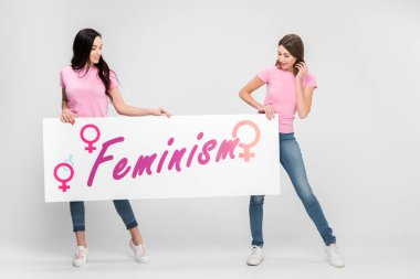 neşeli kadın büyük işareti feminizm yazı ile gri arka plan üzerinde tutan