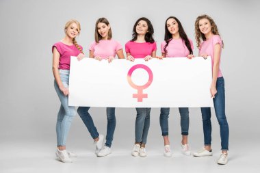attractive young women holding large sign with female symbol on grey background clipart