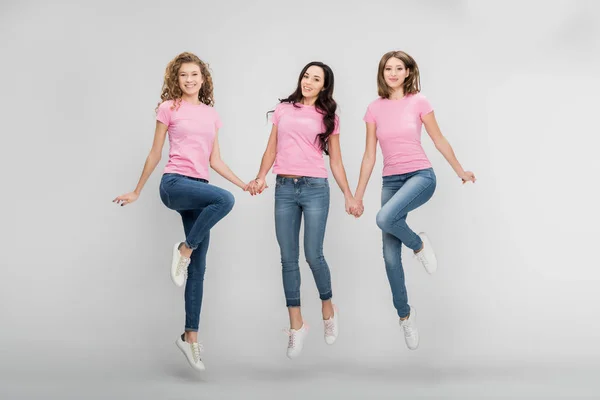 Graciosas Mujeres Jóvenes Cogidas Mano Saltando Sobre Fondo Gris — Foto de Stock