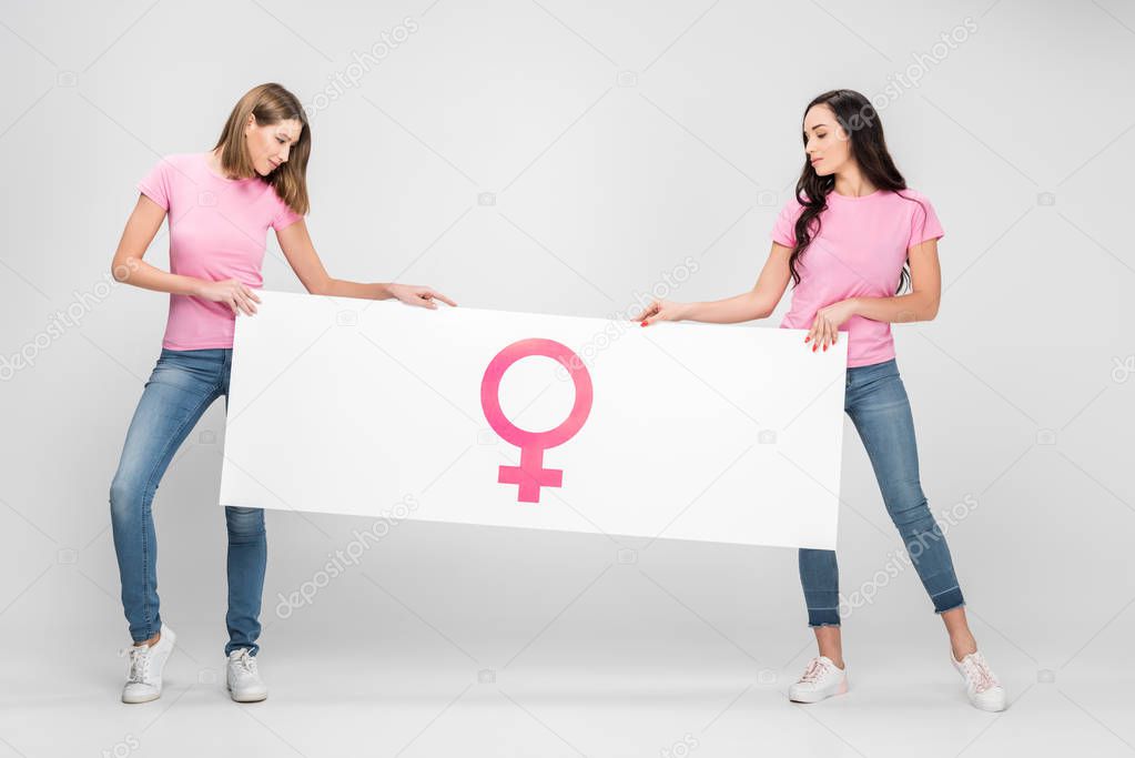 attractive women holding large sign with female symbol on grey background
