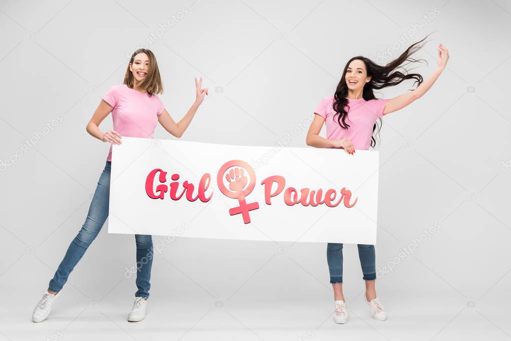 cheerful women holding large sign with girl power lettering on grey background
