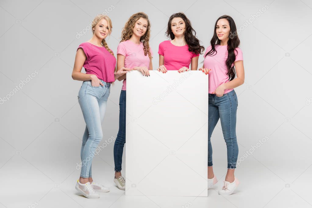 happy girls holding empty board and smiling on grey background