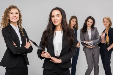 selective focus of cheerful businesswoman holding clipboard near colleague with attractive coworkers standing on background  clipart