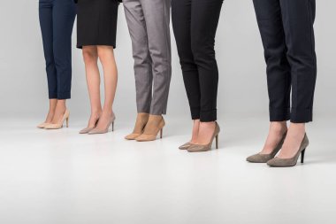 cropped view of women standing in hight heel shoes on grey background clipart