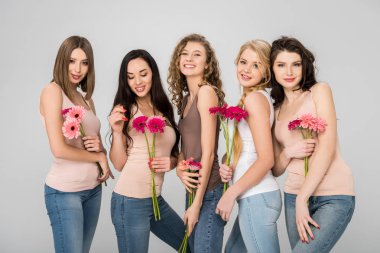 happy young women holding pink flowers and standing isolated on grey clipart