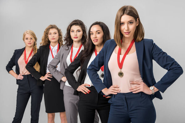 селективная направленность успешных бизнесвумен, стоящих с медалями изолированными на сером
 
