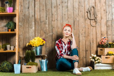 dreamy woman sitting on grass near wooden fence  clipart