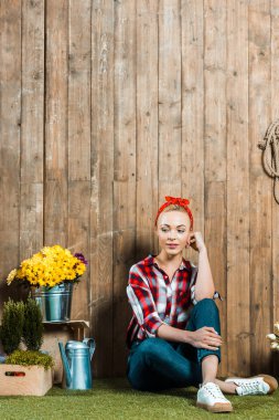 ahşap çit yakınındaki çimenlerin üzerinde oturan dalgın kadın 
