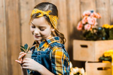 şirin çocuk çit yakınındaki yeşil yaprakları ile küçük fabrikasında arıyorsunuz