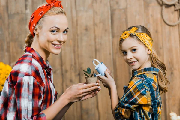 Happy Mother Holding Small Plant While Daughter Watering Toy Watering — Stock Photo, Image