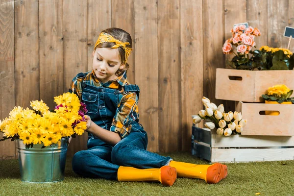 Adorable Niño Mirando Flores Cubo Mientras Está Sentado Hierba Zapatos — Foto de Stock