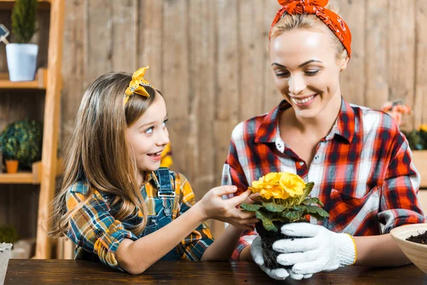 Wesoły Dzieciak Patrząc Szczęśliwą Matką Gospodarstwa Pot Kwiaty Rękach — Zdjęcie stockowe