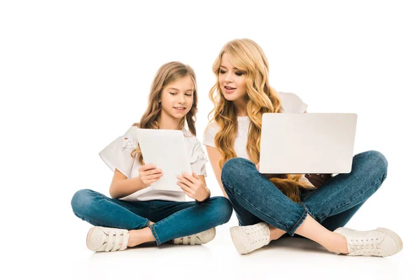 微笑的母亲和女儿使用笔记本电脑和数字平板电脑 而坐在地板上交叉的腿在白色的背景 — 图库照片