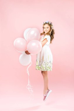 hava balonları ile pembe arka plan atlama hassas beyaz elbiseli çocuk