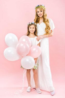 pembe bir arka plan üzerinde güzel annesinin yanında duran Festival hava balonları ile sevimli gülümseyen çocuk