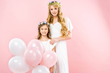 pembe bir arka plan üzerinde güzel annesinin yanında duran Festival hava balonları ile sevimli gülümseyen çocuk