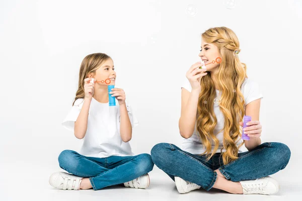 Smiling Mother Daughter Blowing Soap Bubbles While Sitting Floor Crossed — Stock Photo, Image