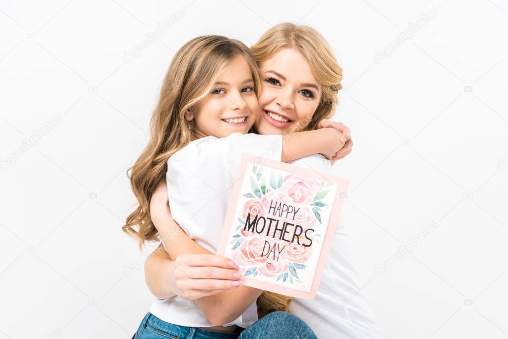 happy beautiful mother holding happy mothers day greeting card and hugging adorable daughter on white background 