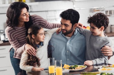 neşeli İspanyol Aile Evde yemek sarılma gülümseyen