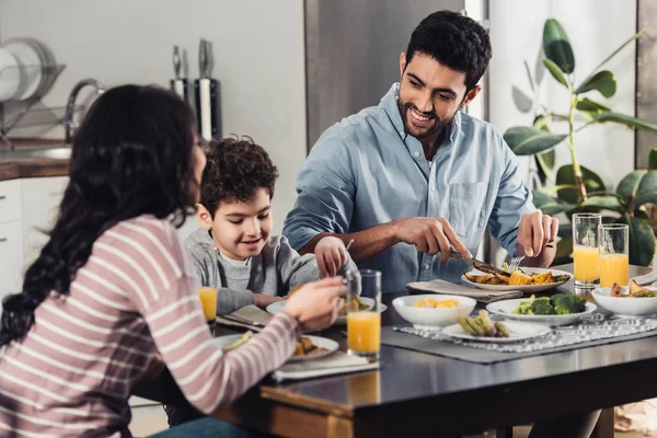 Guapo Padre Latino Mirando Feliz Hijo Mientras Almorzando Cerca Esposa —  Fotos de Stock