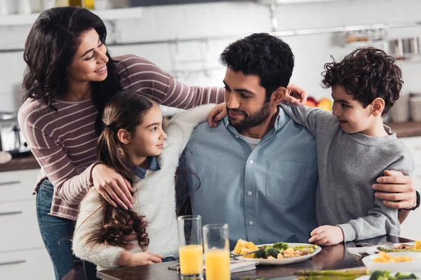 Alegre Familia Hispana Sonriendo Mientras Abraza Cerca Del Almuerzo Casa —  Fotos de Stock