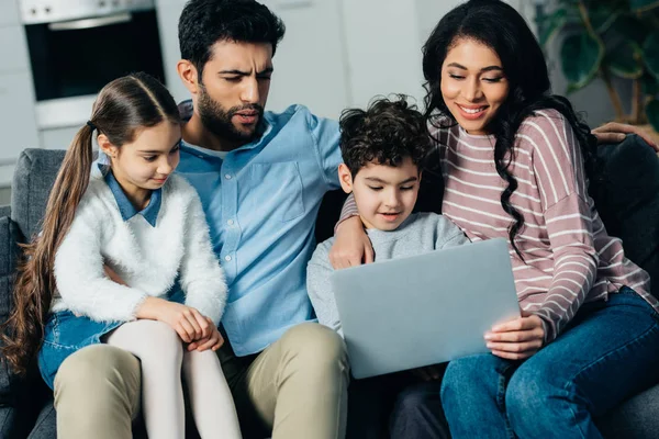 愉快的西班牙家庭坐在沙发上 看着笔记本电脑在家里 — 图库照片