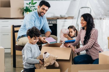 happy latin family unpacking boxes in new home  clipart