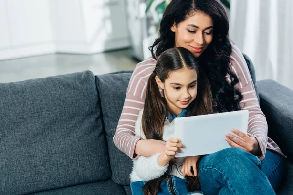 Lateinische Frau Sitzt Mit Tochter Auf Sofa Und Benutzt Hause — Stockfoto