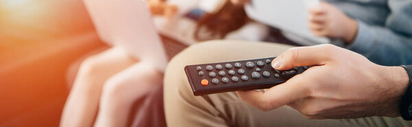cropped view of man holding remote control in hand near family