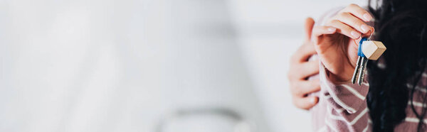 cropped view of woman holding keys from new home near husband