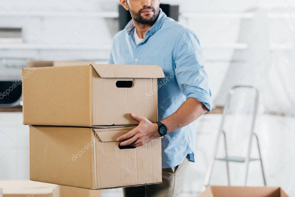cropped view of man holding boxes while moving in new home 