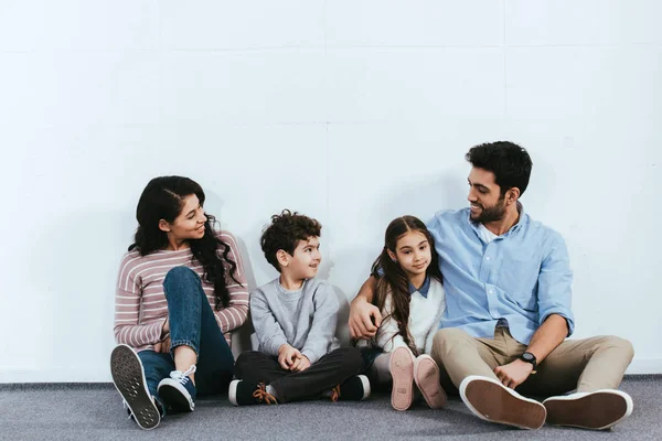 Χαρούμενα Ισπανόφωνος Οικογένεια Κάθεται Στο Πάτωμα Κοντά Στο Λευκό Τοίχο — Φωτογραφία Αρχείου