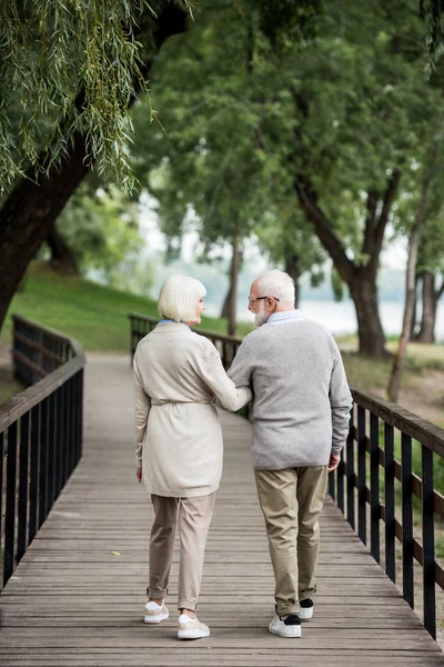 Senior Couple Talking While Walking Wooden Bridge Park — Stock Photo, Image