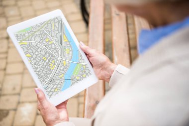selective focus of senior woman holding digital tablet with map on screen clipart