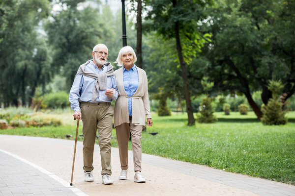 happy stylish senior couple enjoying walking in park