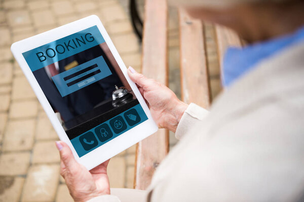 избирательный фокус пожилой женщины с использованием цифрового ноутбука с бронированием на экране
