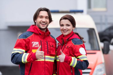 Laughing paramedics in red uniform showing thumbs up clipart