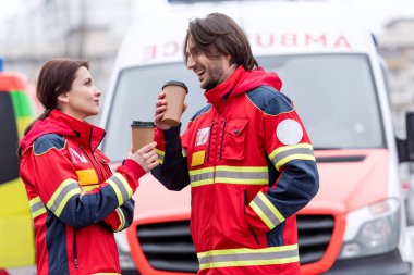 Sağlık görevlileri ambulans araba önünde kahve içme gülümseyen