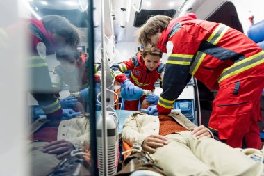 Paramedics doing cardiopulmonary resuscitation in ambulance car clipart