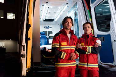 Ambulans araba yakınındaki kırmızı üniforma ayakta yorgun sağlık görevlileri