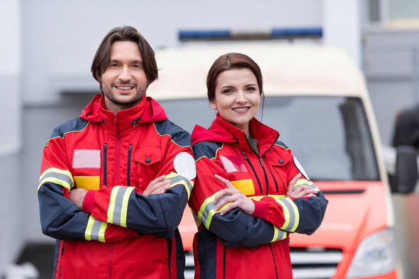 Smiling paramedics in uniform standing with crossed arms