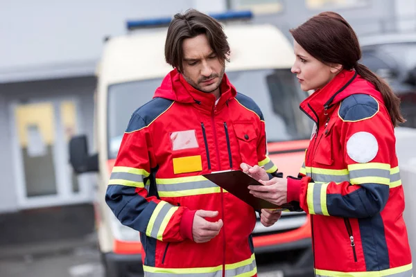 Ernstige Paramedici Rode Uniform Lezen Van Notities Klembord — Stockfoto