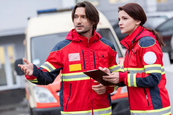 Ambulanspersonal Röd Uniform Talar Och Tittar Bort Gatan — Stockfoto